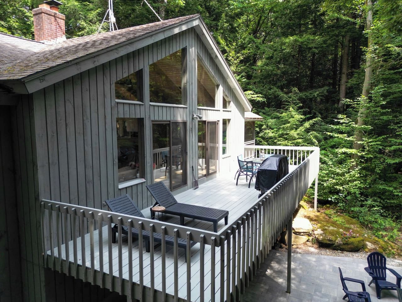 A wooden cabin with a deck, large windows, and outdoor seating.