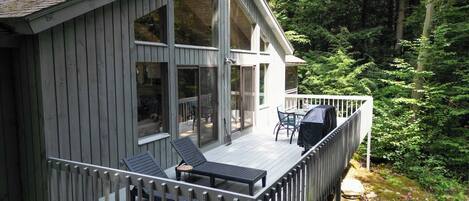 A wooden cabin with a deck, large windows, and outdoor seating.