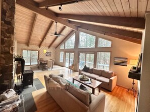 A spacious living area with a stone wall, a fireplace, a sofa, a coffee table, and a television.