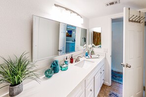 A bathroom with a white sink, a large mirror, a potted plant, and a towel rack. - Relaxing desert retreat with golf, gas grill, and pool (Indio)