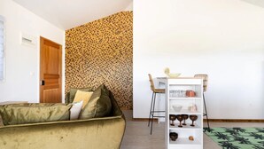 Una sala de estar con un sofá verde, una puerta de madera y un papel tapiz estampado.