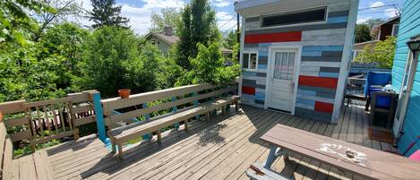 A wooden deck with a bench and a small building with a colorful exterior.