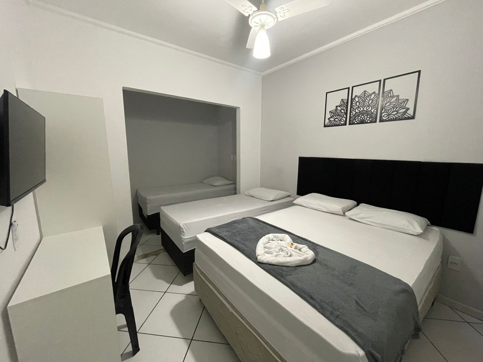 Un dormitorio con dos camas individuales, televisión y ventilador de techo.