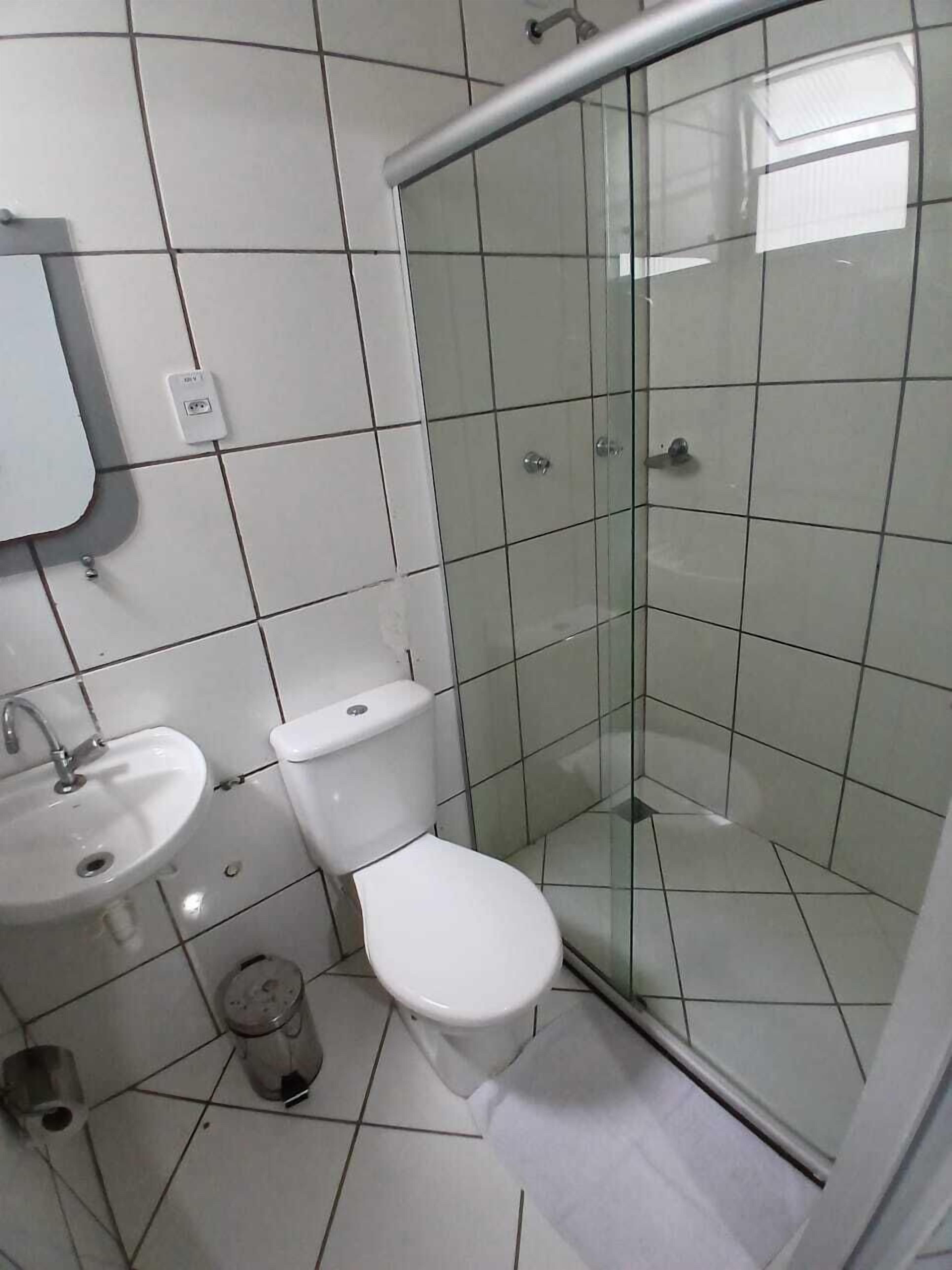 A bathroom with a toilet, sink, and glass shower enclosure.
