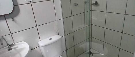 A bathroom with a toilet, sink, and glass shower enclosure.