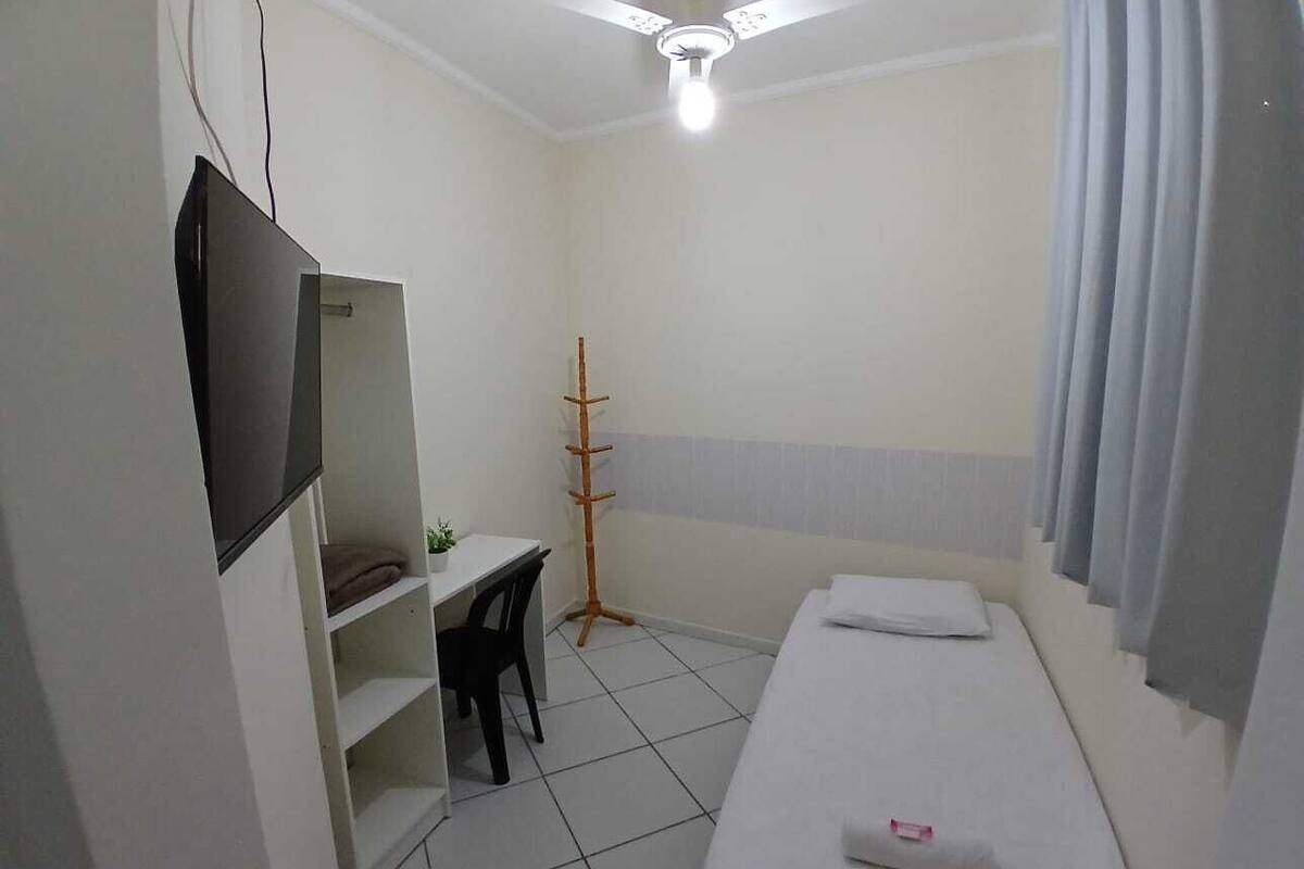 A small, clean room with a bed, a desk, and a TV.