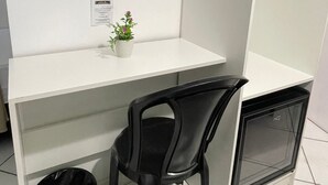 A white desk with a black chair, a television mounted above, and a small potted plant on the desk. - Hotel Aconchegante (Jequie)