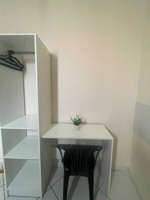 A small room with a white desk, a black chair, and a potted plant on the desk. - Hotel Aconchegante (Jequie)