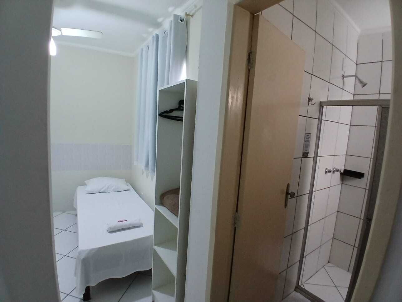 Una habitación pequeña y limpia con una cama individual, ducha y armario.