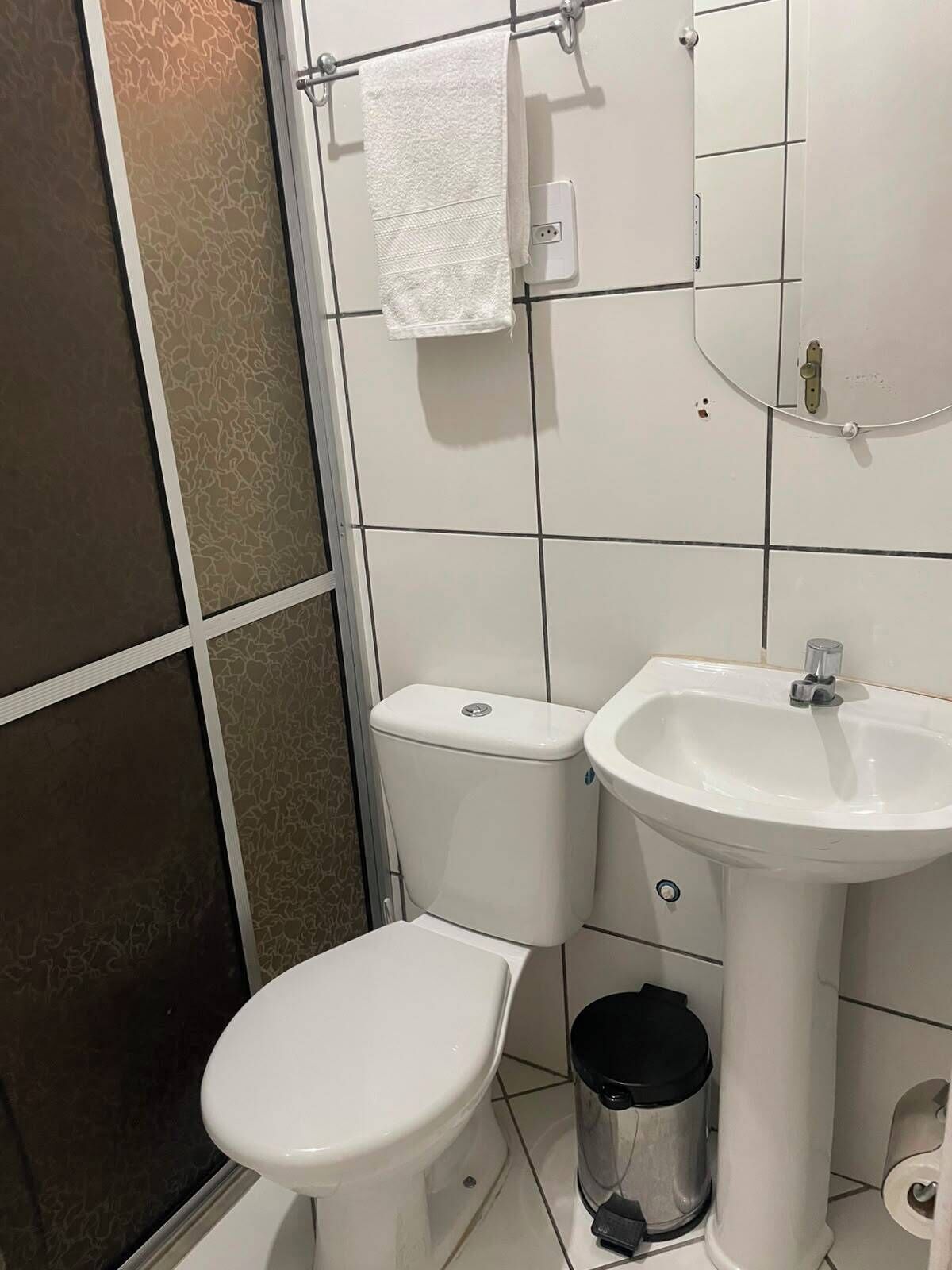 A bathroom with a toilet, sink, and a trash bin.