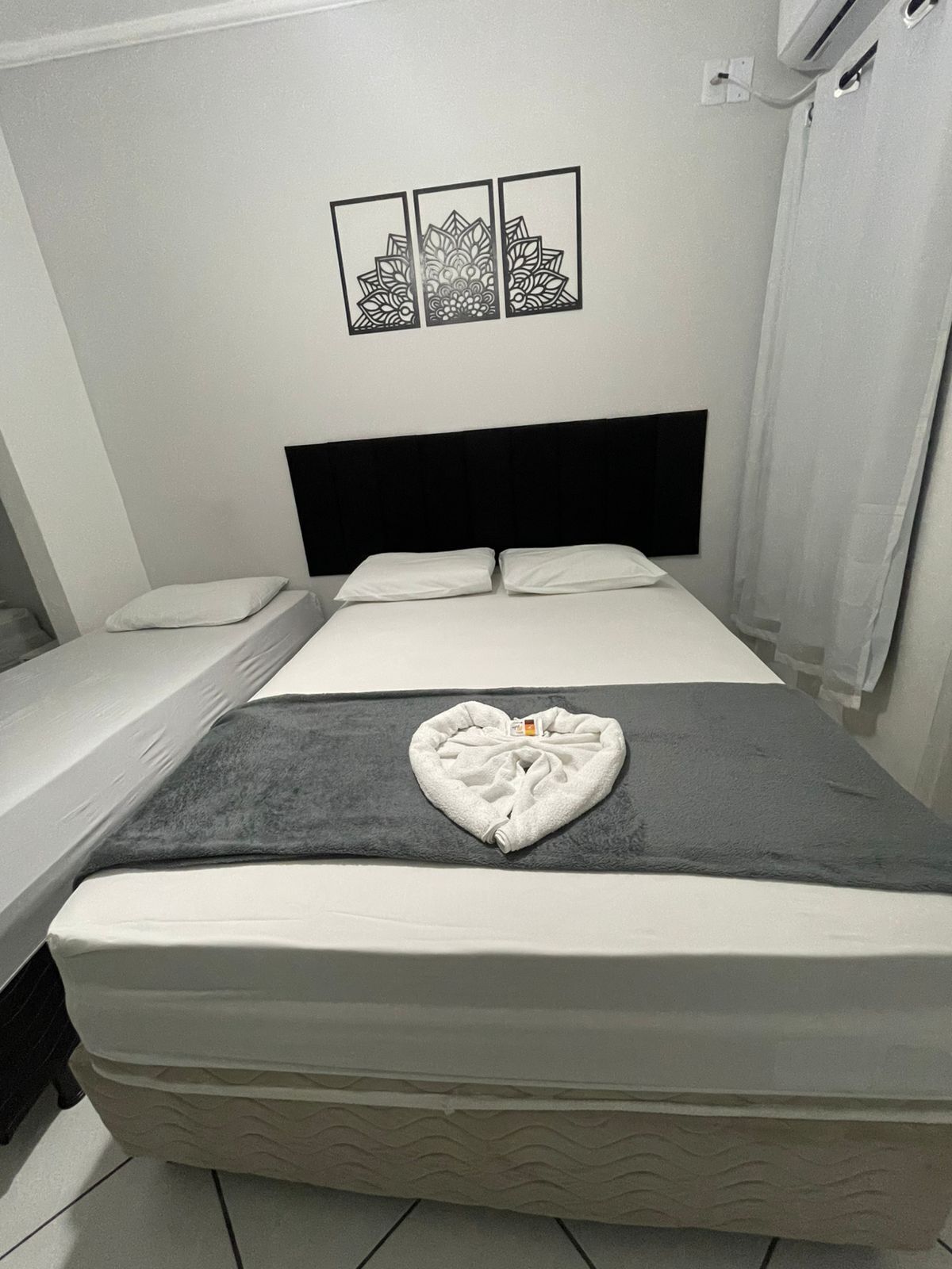 Habitación de hotel con cama, dos mesitas de noche, cabecero y tres cuadros colgados en la pared.