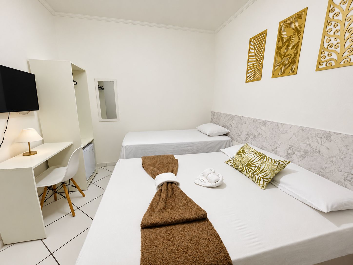 A hotel room with a bed, a desk with a chair, a television, and decorative wall panels.
