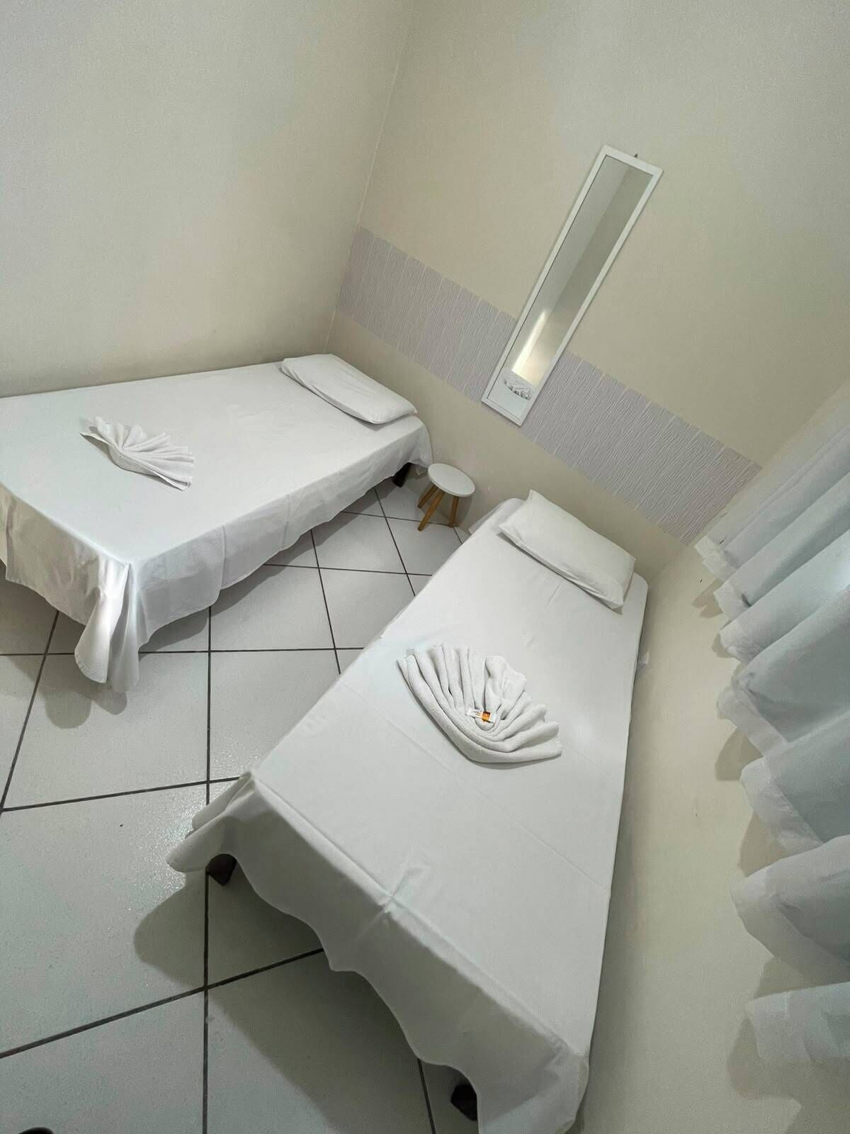 A hotel room with two beds, each with a neatly folded towel.