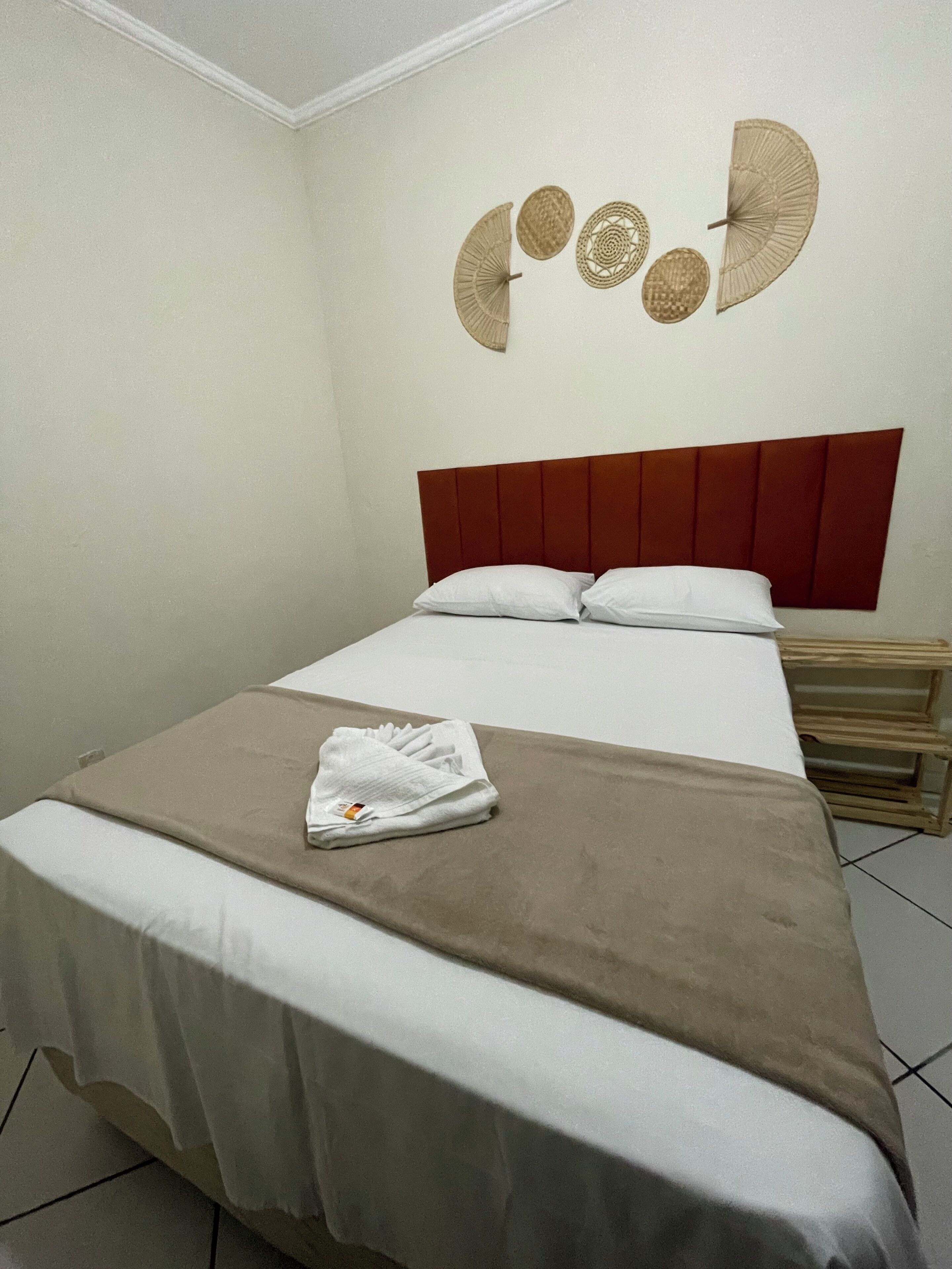 Een hotelkamer met een bed, nachtkastje en decoratie aan de muur.