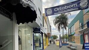 A paved street with storefronts, including a visible hotel entrance and a sign for Ortobom. - Hotel Aconchegante (Jequie)