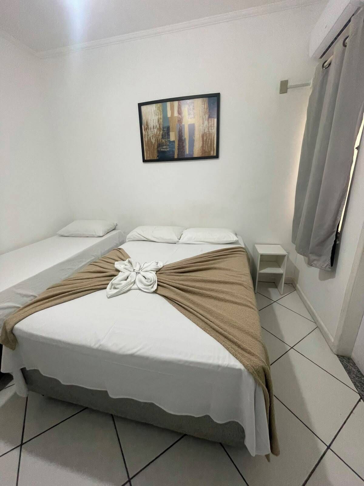 A hotel room with a bed, a nightstand, and a painting on the wall.