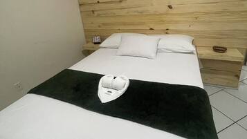 A hotel room with a wooden headboard, a bed with white bedding, and a towel on the bed.