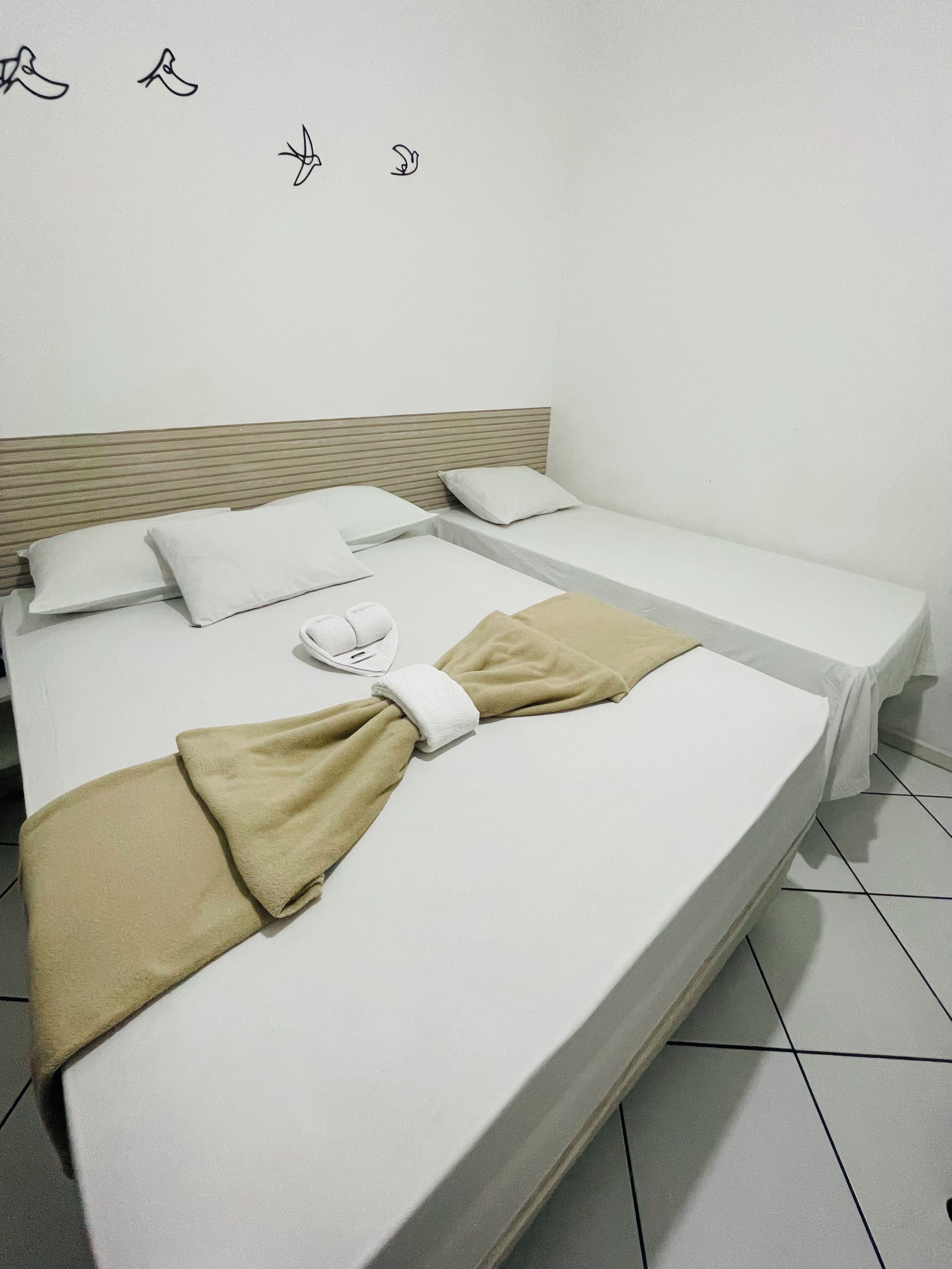 A single bed with a white mattress, two pillows, a beige towel, and a white pillowcase.