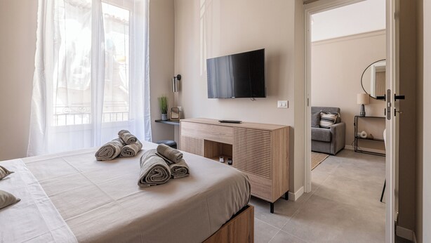 Una habitación de hotel moderna con cama, televisor, escritorio y sofá.