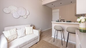 Eine moderne Küche mit weißer Arbeitsplatte, zwei Barhocker und einem weißen Sofa mit Zierkissen.