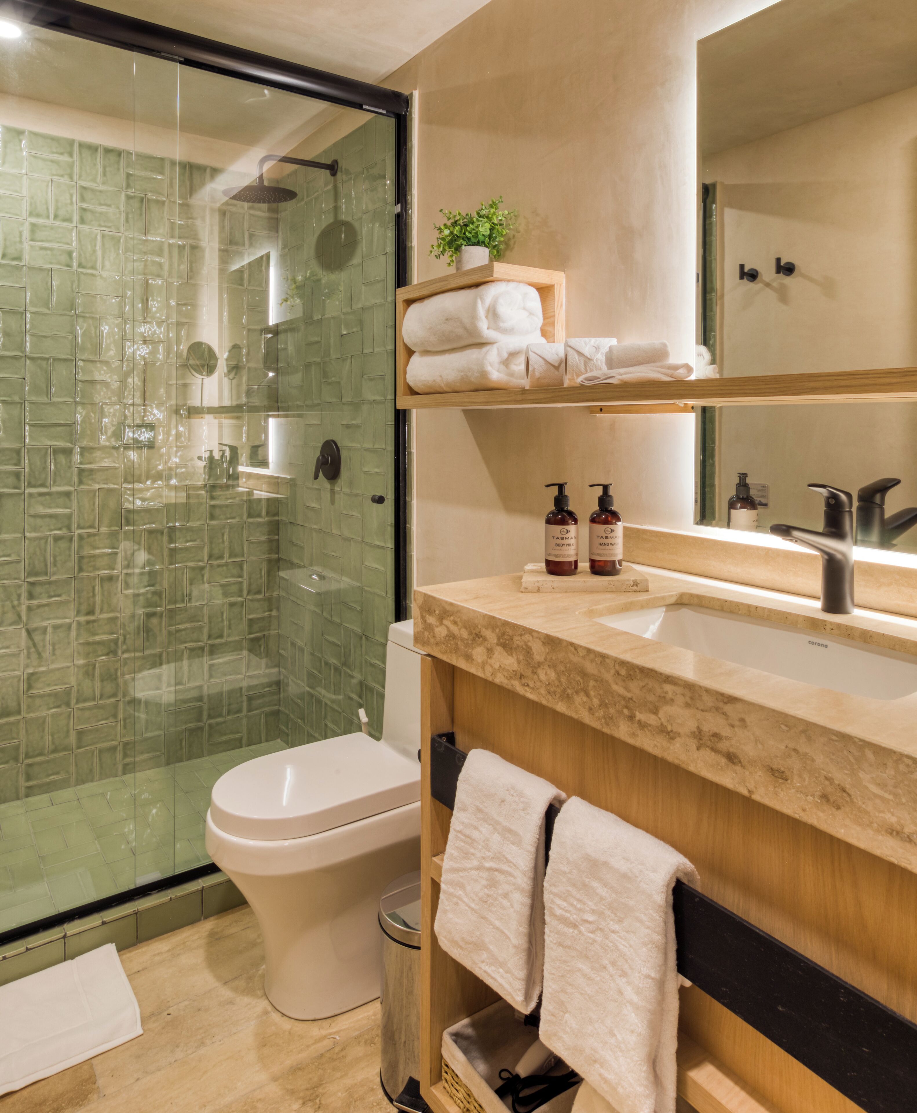 Une salle de bain moderne avec une douche à parois de verre, des toilettes, un lavabo avec un miroir et un porte-serviettes.