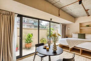 Ein Hotelzimmer mit Balkon, einem Bett, einem Esstisch und Topfpflanzen.