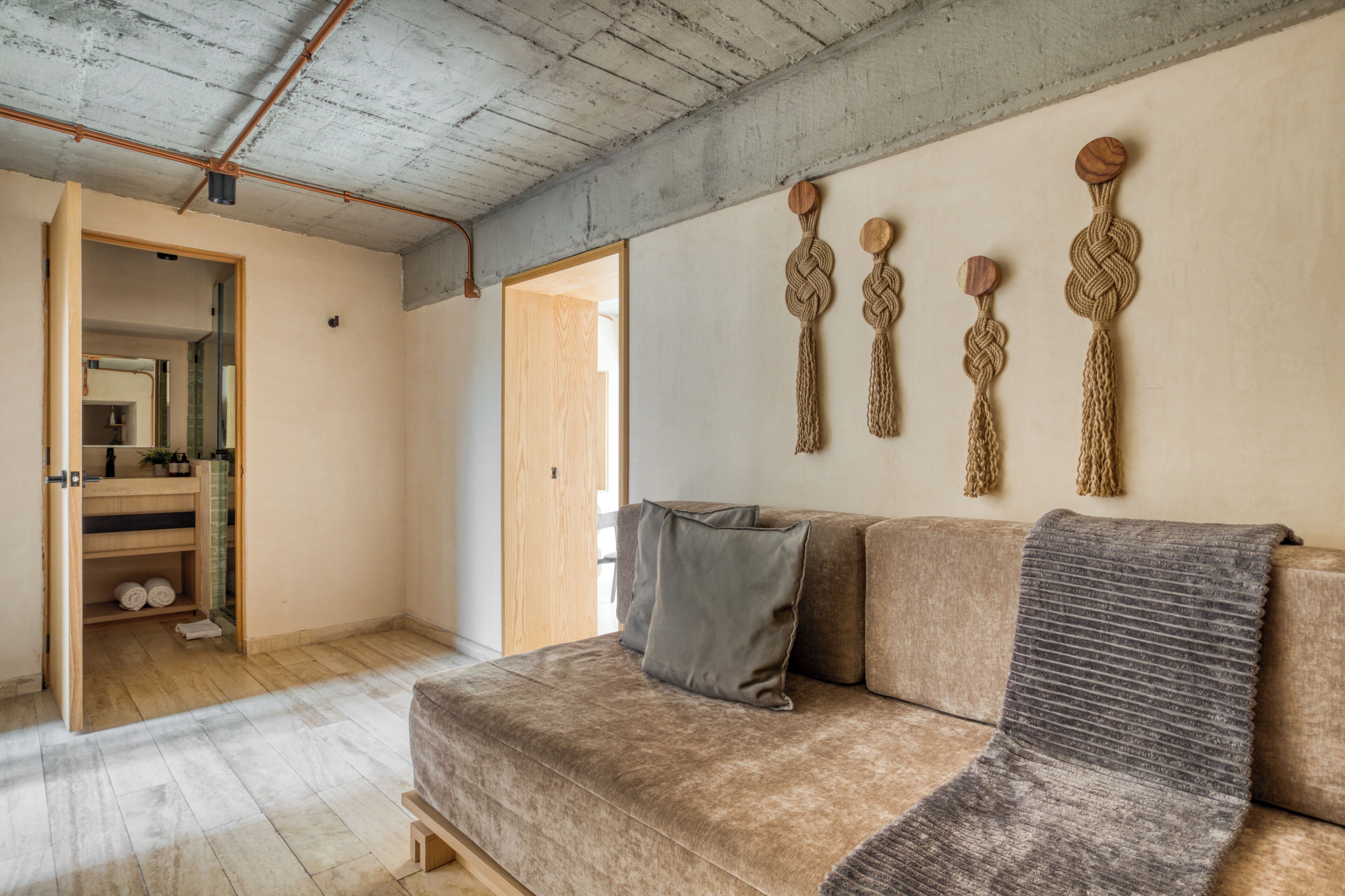 A modern living room with a beige sofa, a grey throw blanket, and wooden wall decor.