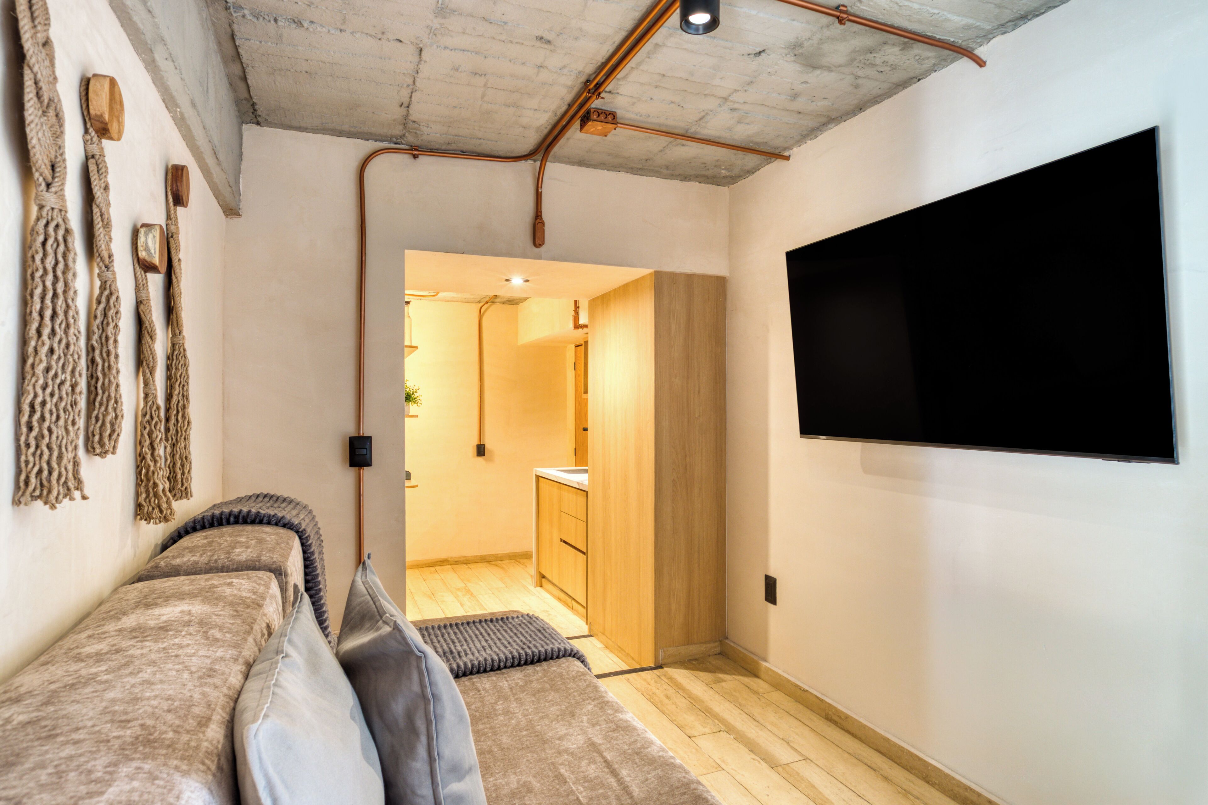 A modern interior with a sofa, a flat-screen TV, and a visible kitchen area.