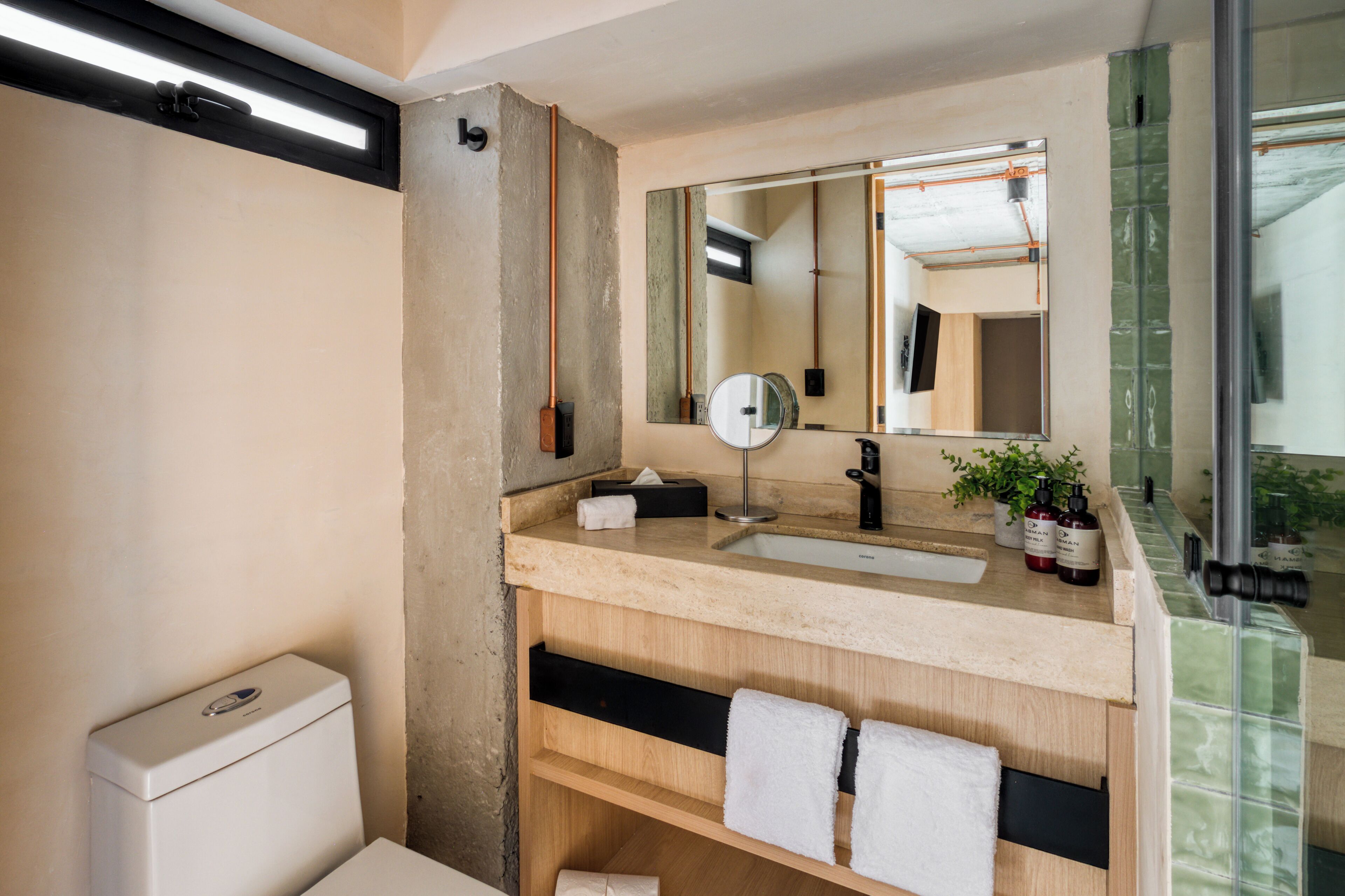 A modern bathroom with a large mirror, a sink, and a toilet.