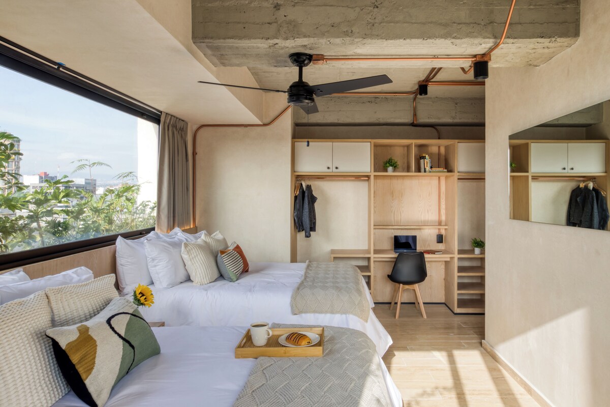 Habitación de hotel moderna con una cama grande, un escritorio y vistas a la ciudad.