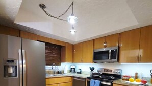 A modern kitchen with stainless steel appliances, wooden cabinets, and granite countertops. - Island life 2 br 2-ba walk 2 beach, Snorkel & Surf (West Palm Beach)