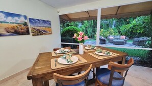 A dining area with a wooden table set for four, surrounded by chairs with blue cushions. - Island life 2 br 2-ba walk 2 beach, Snorkel & Surf (West Palm Beach)