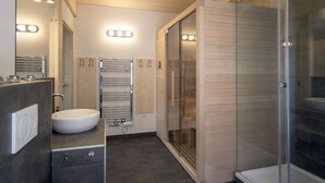 Une salle de bain moderne avec un lavabo, des porte-serviettes et une douche à parois de verre.