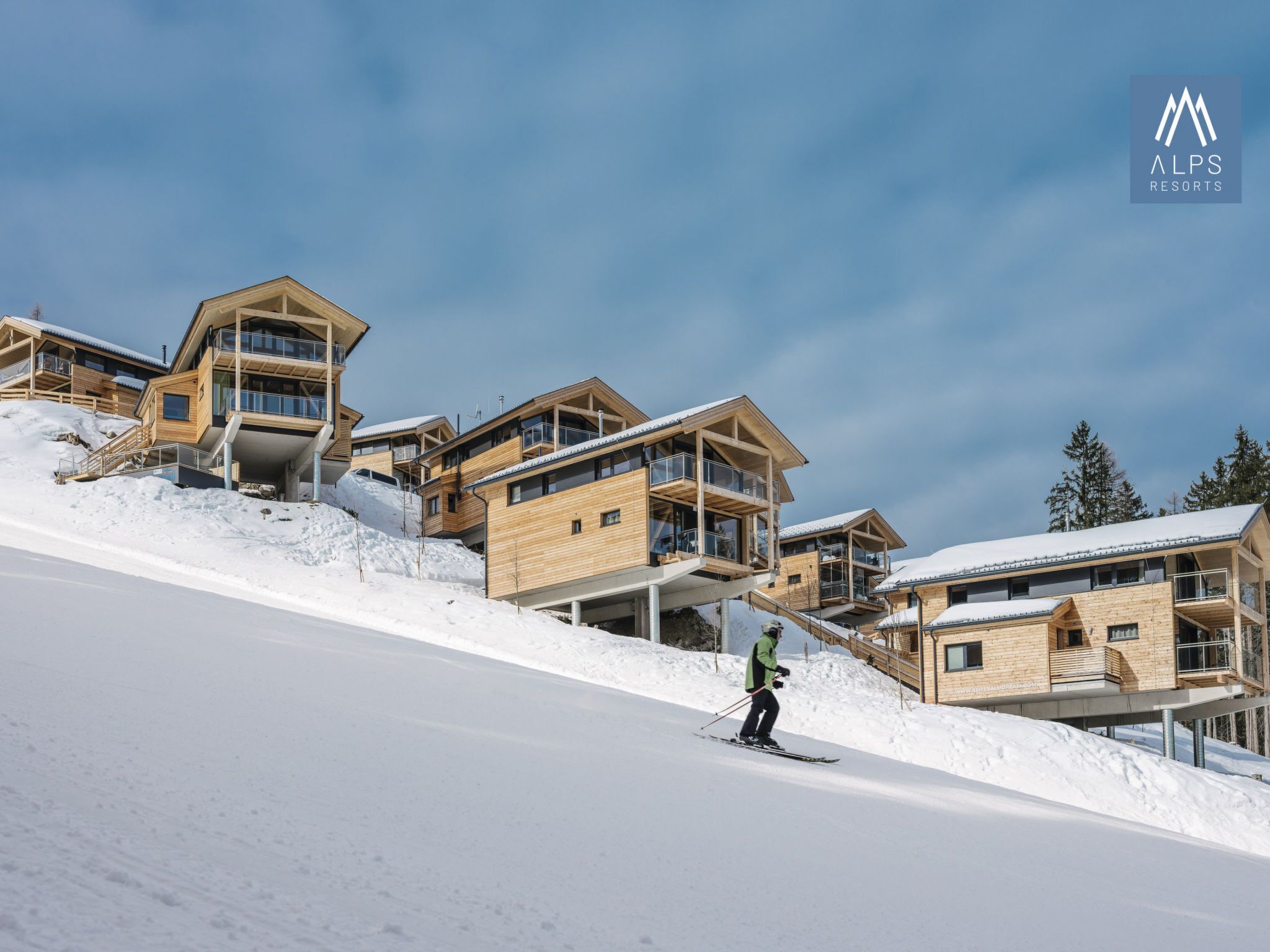 Un centro de esquí con edificios de madera, pistas nevadas y cielo despejado.