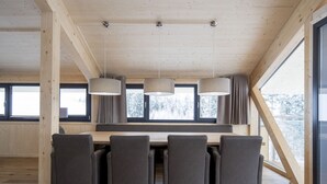 Un espace de restauration moderne avec une table et des chaises en bois, de grandes fenêtres et des luminaires suspendus.