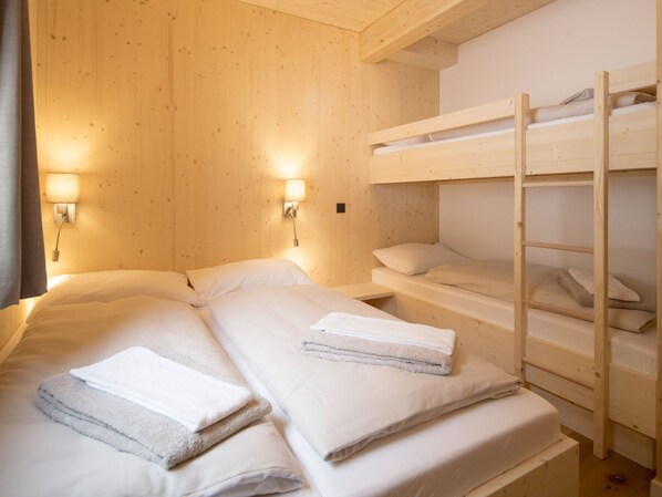 Una habitación de cabaña de madera con literas y dos mesitas de noche.