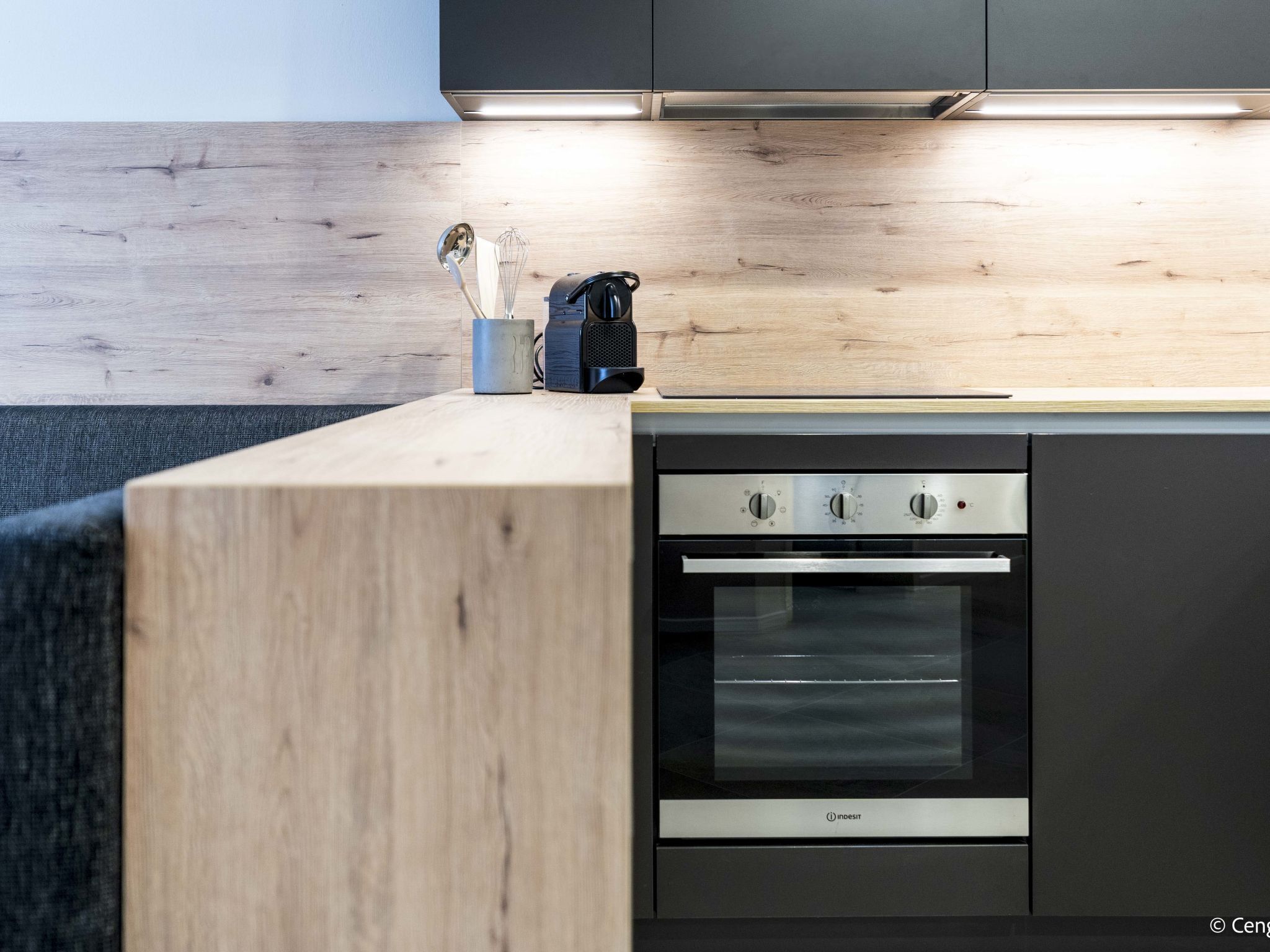 A modern kitchen with a built-in oven, a wooden countertop, and a coffee maker.