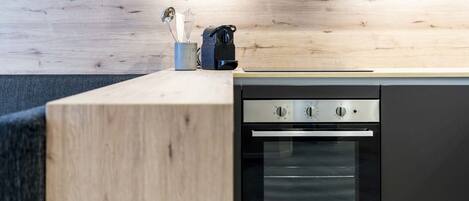 A modern kitchen with a built-in oven, a wooden countertop, and a coffee maker.