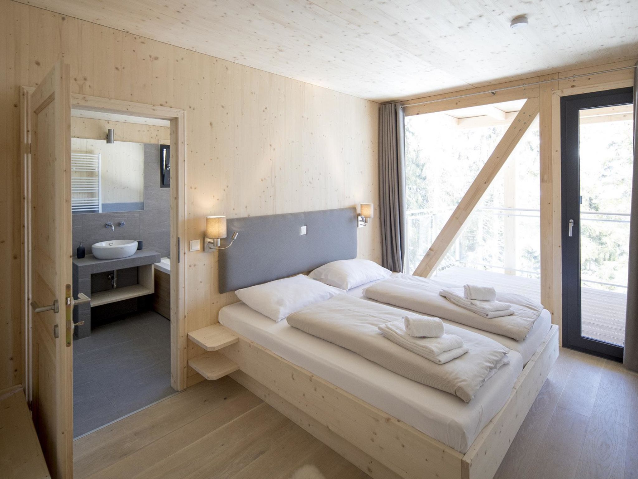 Une pièce en bois avec un lit, une salle de bain et un balcon.