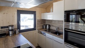 Une cuisine moderne avec des murs en bois, une fenêtre, des appareils électroménagers en acier inoxydable et un four encastré.