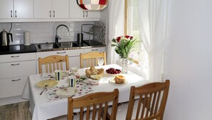 Cucina con mobili bianchi, un piano di lavoro nero, un lavello e una finestra con tende bianche.