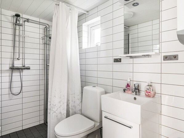 A bathroom with a shower, toilet, and sink.