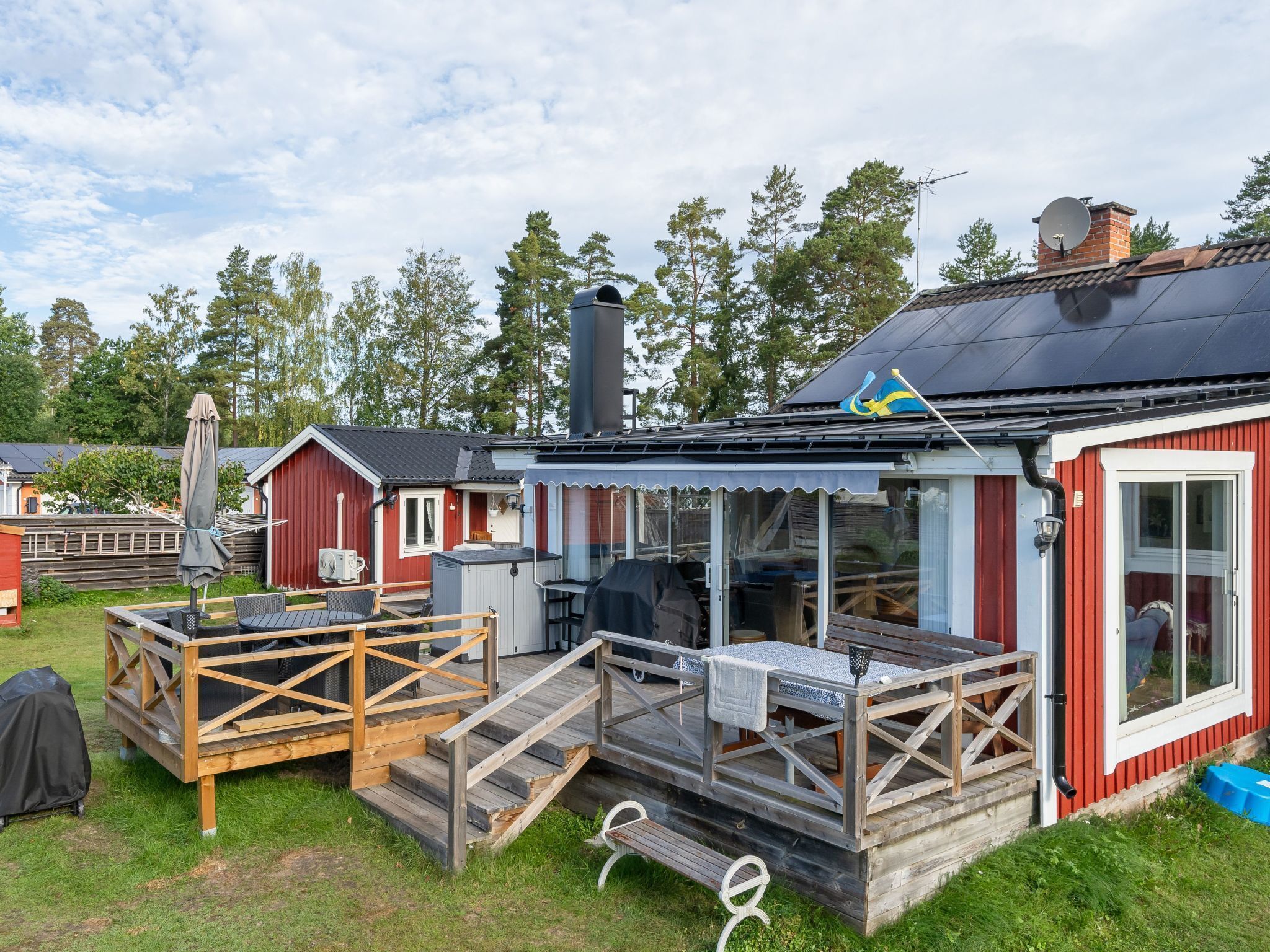 A compact cabin with a small deck, a grill area, and a red exterior.