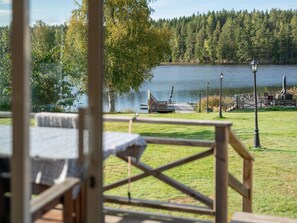 A lakeside view with a wooden deck, a gazebo, and a dock extending into the water.