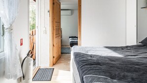 Ein Schlafzimmer mit einem Bett, einer Holztür, einem Fenster mit Vorhängen und einem Feuerlöscher an der Wand.