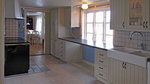 Una cucina con mobili bianchi, una stufa nera e una finestra con vista.