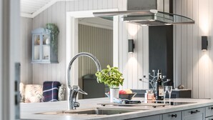 Et moderne køkken med vask i rustfrit stål, indbygget ovn og et stort spejl over bordpladen.