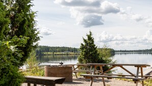 Picnicområde ved søen med træbænke og bålsted.