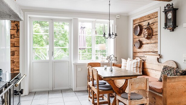 A dining area with a wooden table and chairs, a bench, and a wall-mounted clock. - Klinten Totebo by Interhome (Totebo)