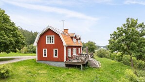 A red wooden house with a porch and steps, surrounded by greenery and a clear sky. - Klinten Totebo by Interhome (Totebo)